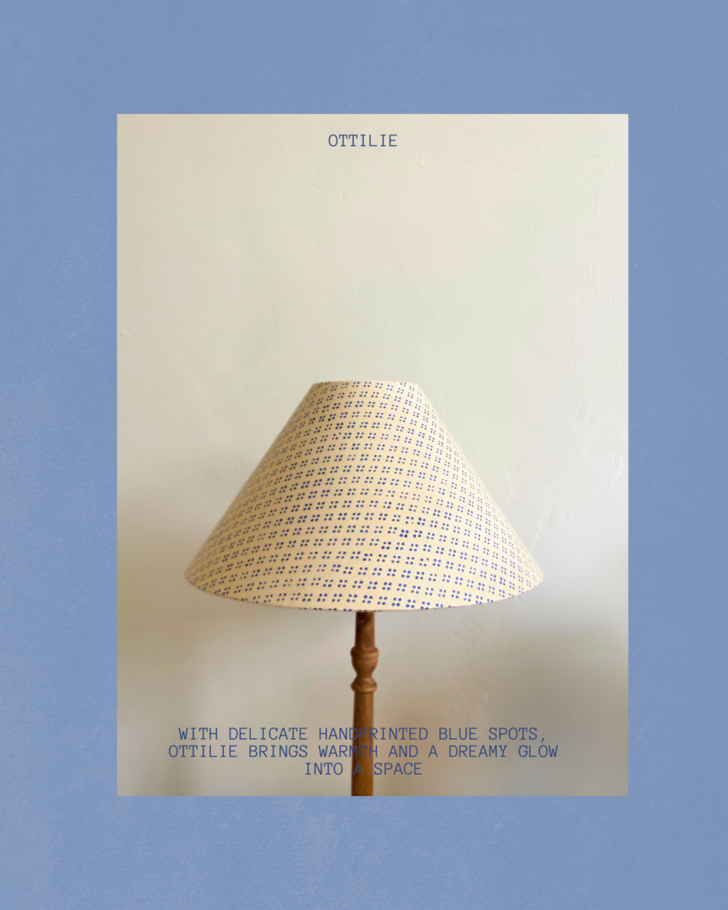 A lamp with a beige shade featuring delicate blue hand-painted spots, shown against a cream background with blue text reading 'OTTILIE' and a descriptive tagline below.